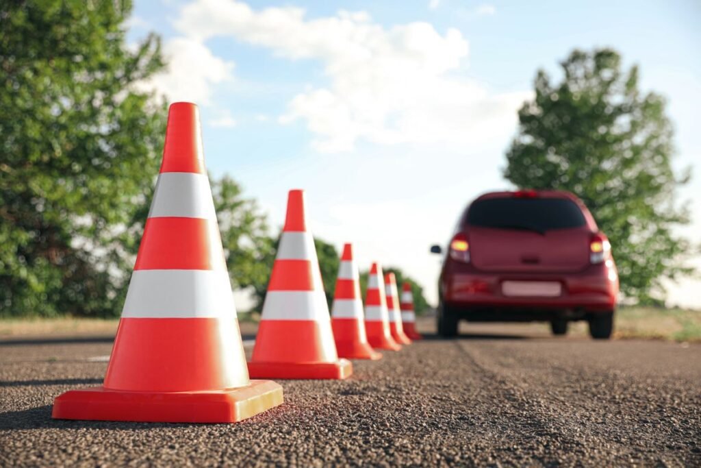 Row of traffic cones beside a red car on a practice road, showing what happens on a driving test
